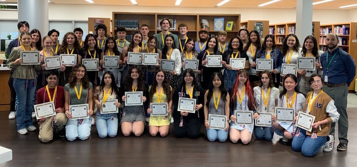 Image of all the students who earned the NYS Seal of Biliteracy in 2024. They are posed in the high school's iLc.